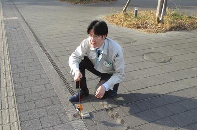 土木職の職員が道路で測定作業をしている写真